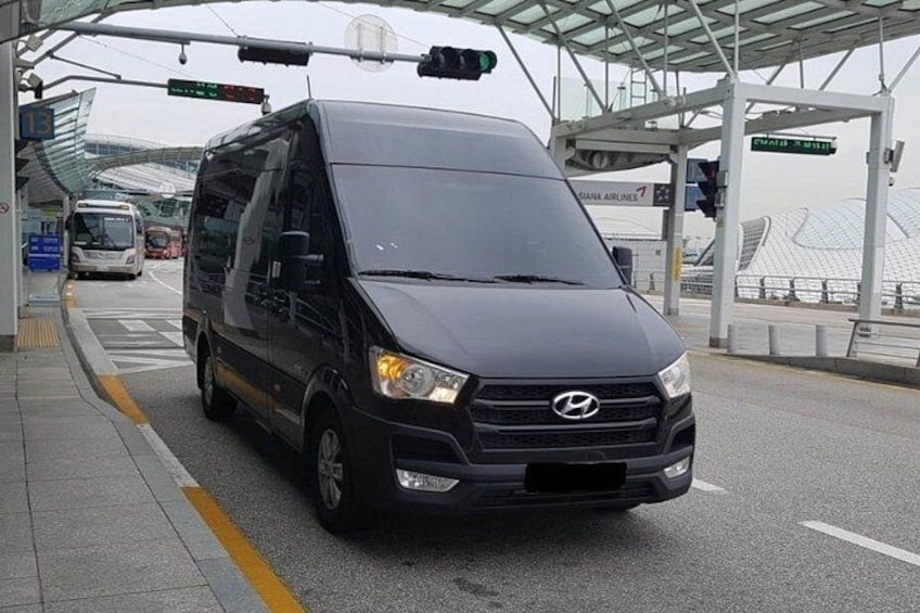 A black van parked at a toll booth with a glass roof structure in the background. 4