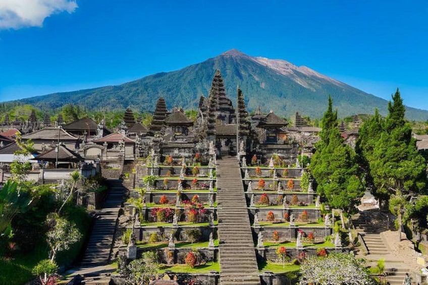A temple complex with a staircase leading up to a central structure, surrounded by lush greenery and a mountain in the background. 4