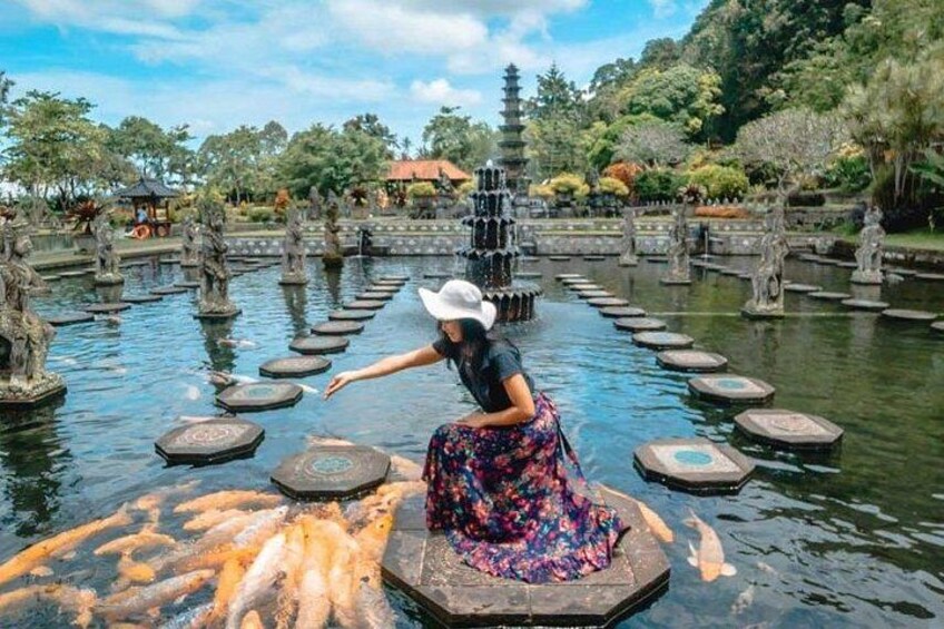 A woman feeding koi fish in a pond with stepping stones and pagodas in the background. 5