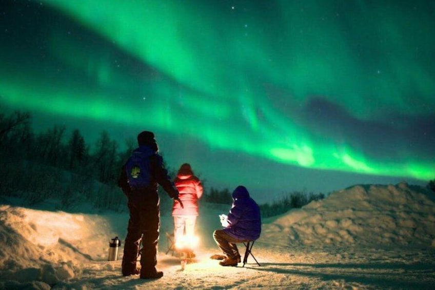 Dos personas observando las auroras boreales en un paisaje nevado. 2