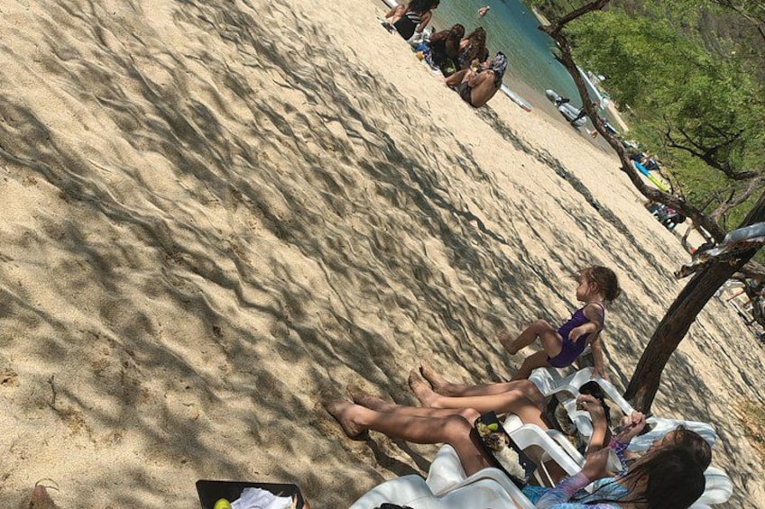 Ein sandiger Strand mit Menschen, die sitzen und sich sonnen. 3