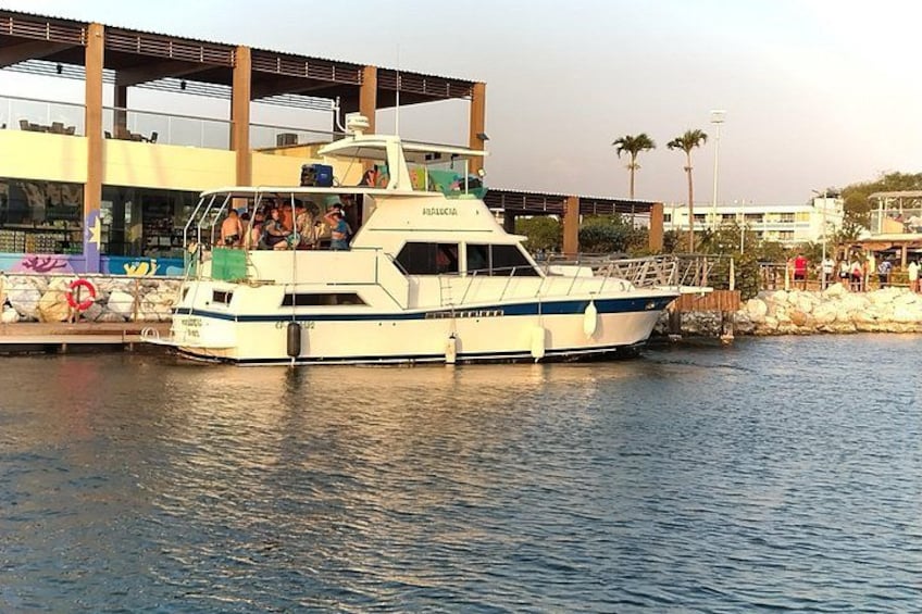 Ein weißes Boot liegt an einem Steg, Passagiere sind an Bord. 2