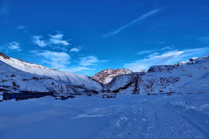 Een besneeerd berglandschap met een helderblauwe lucht en een weg die naar een bergpas leidt. 3
