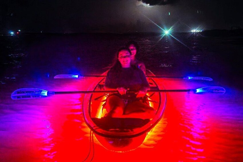 Iemand roeit in een boot op het water 's nachts, met kleurrijke verlichting. 3