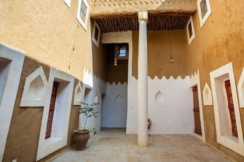 A courtyard with a central column, decorative arches, and a potted plant. 4