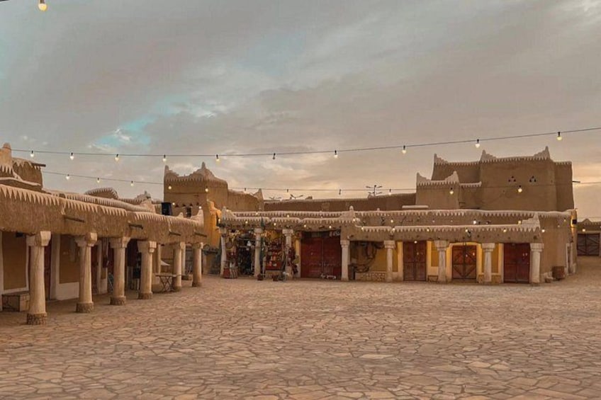 A courtyard with traditional architecture, including thatched-roof buildings and stone flooring. 5