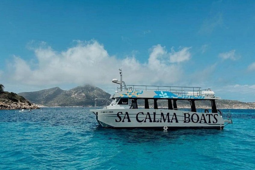 Un bateau blanc sur lequel on peut lire « SA CALMA BOATS » sur le côté, naviguant sur une eau d’un bleu limpide, avec un paysage montagneux en arrière-plan. 2