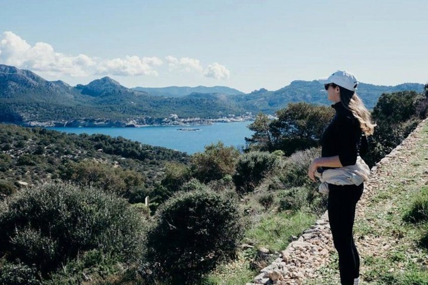 Une personne se tient sur un sentier surplombant un lac, entouré de collines. 4