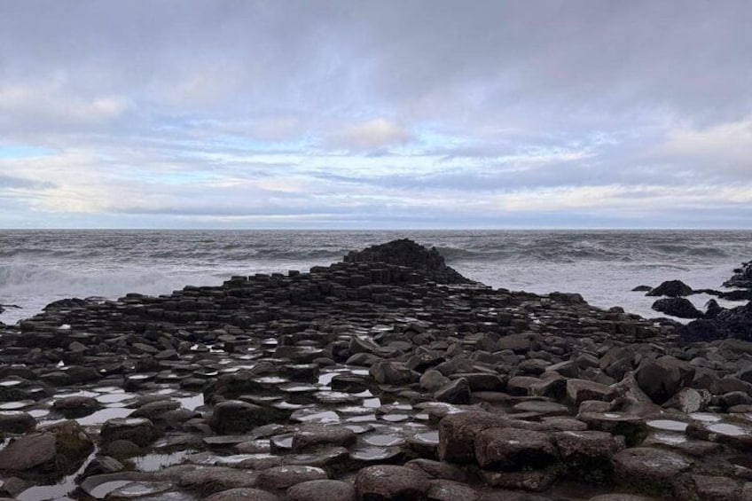 A rocky shoreline with large boulders and waves crashing against the rocks. 2