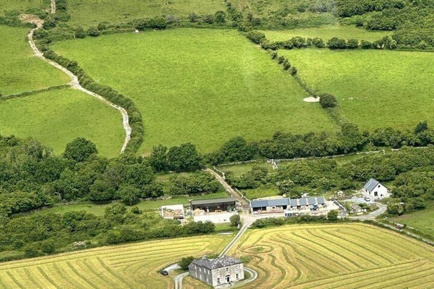 A rural landscape with fields, a winding path, and a cluster of buildings. 4