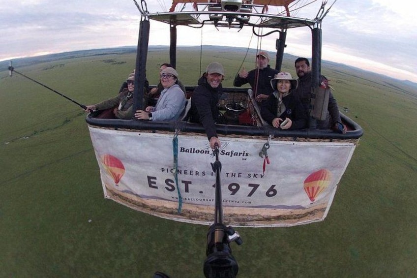 A hot air balloon with passengers, a grassy field, and a clear sky. 1