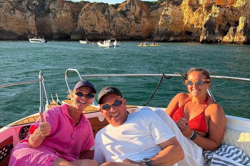 A boat with three people on a rocky coastline with boats in the background. 3