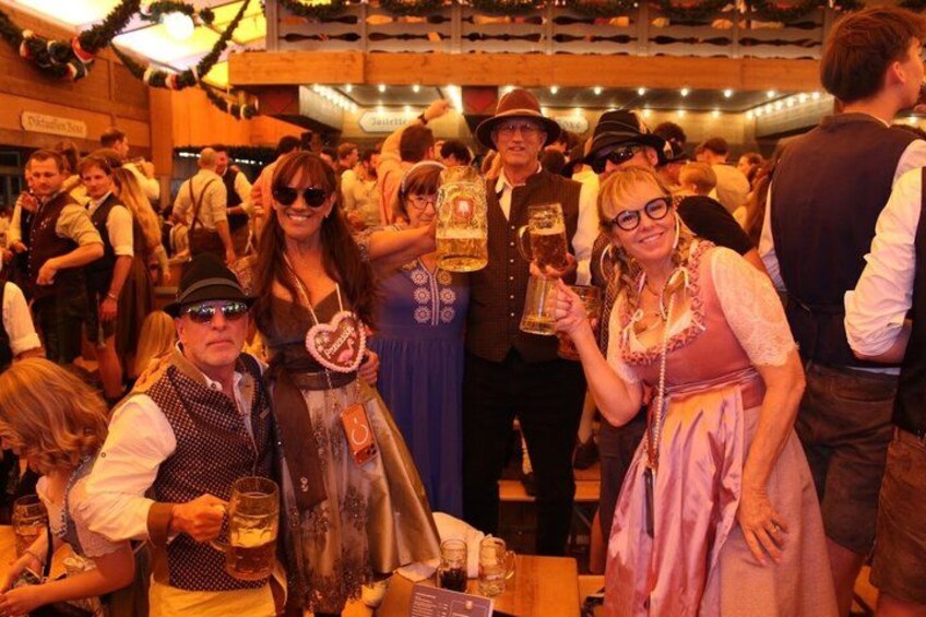 A crowded indoor event with people dressed in traditional attire, holding beer mugs. 4
