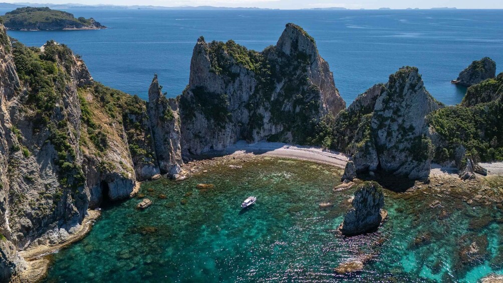 A coastal landscape with clear turquoise waters, rocky cliffs, and a boat in the bay. 1