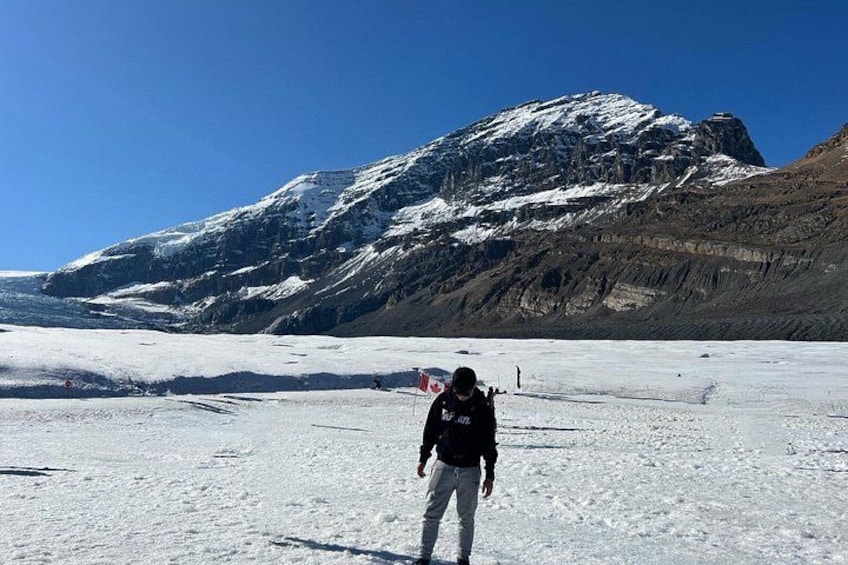 Een persoon staat op een met sneeuw bedekte gletsjer, met een berg op de achtergrond. 3