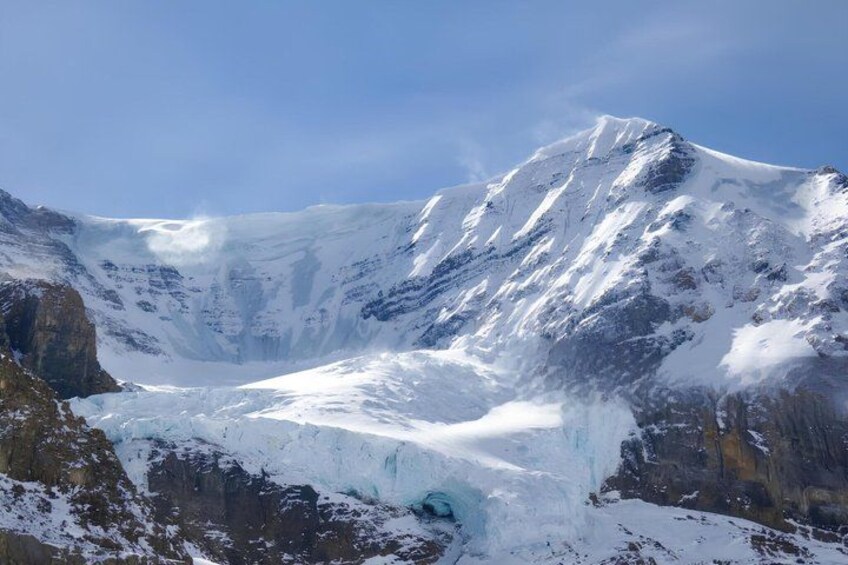 En glaciär med ett brant, snötäckt berg i bakgrunden. 1
