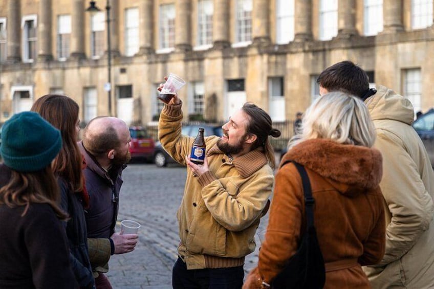 Un grupo de personas al aire libre, una sosteniendo una botella y un vaso de plástico, con un edificio histórico al fondo. 1