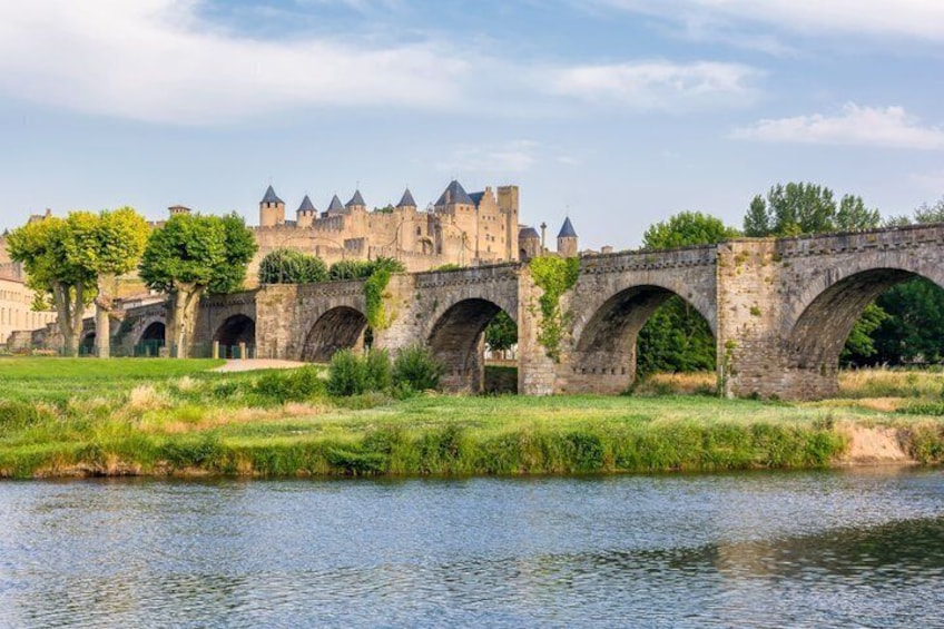 Eine historische Steinbrücke mit Bögen, im Hintergrund ein Schloss und im Vordergrund ein Fluss. 2