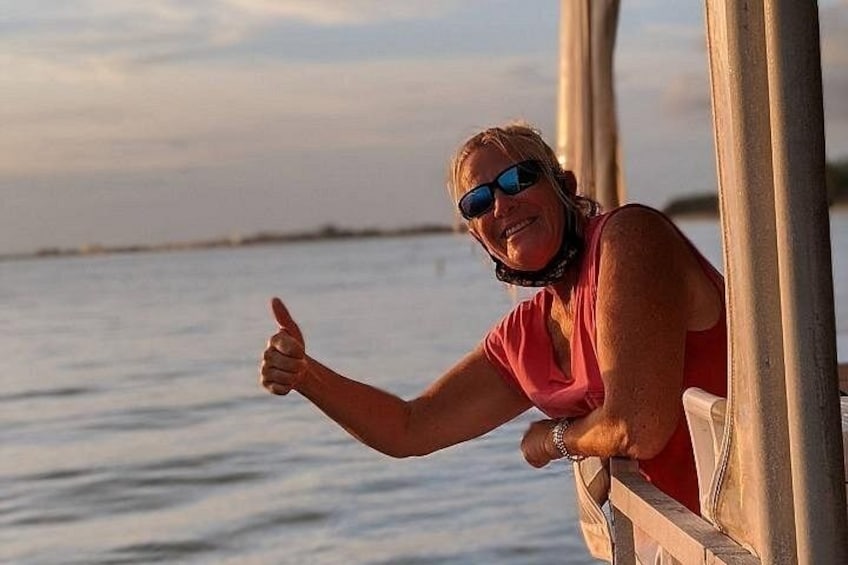 A person leaning on a wooden pier with a body of water in the background. 1