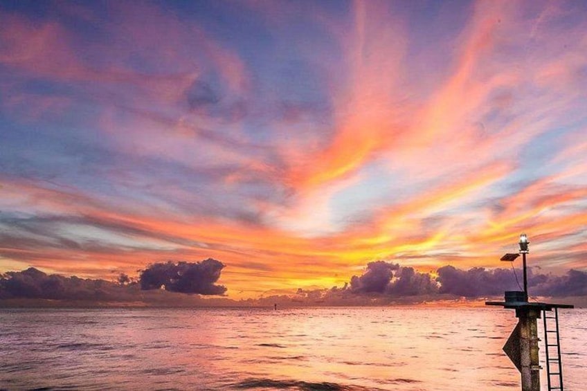 A sunset over a body of water with a lighthouse in the foreground. 3