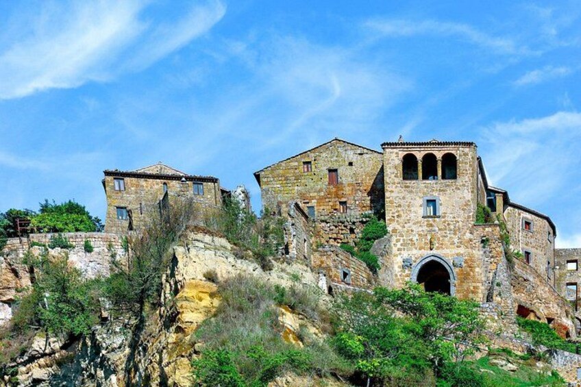 A historic stone building with multiple levels, situated on a rocky hillside. 4