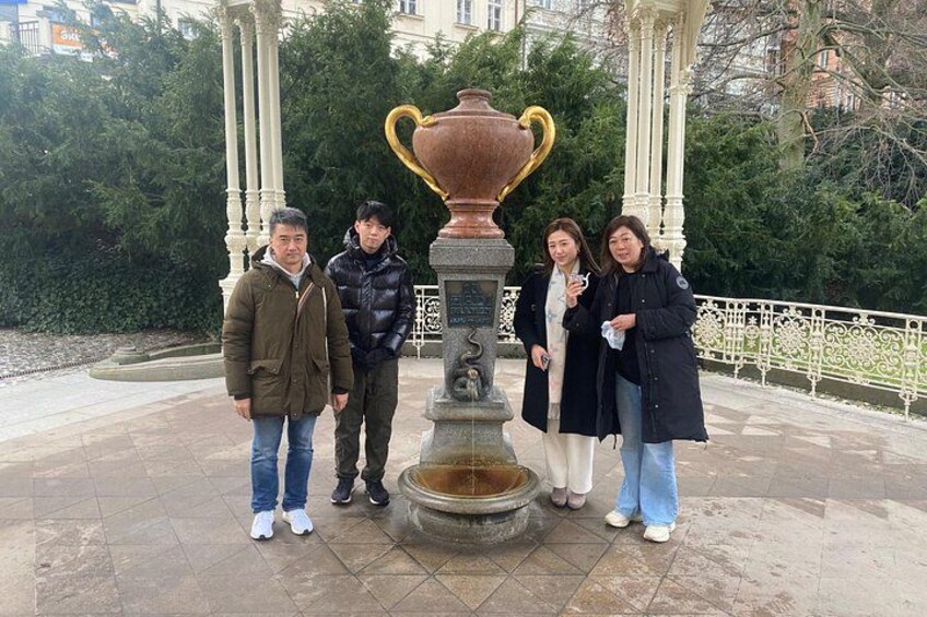 Eine Gruppe von Menschen steht vor einem Brunnen mit einer großen Vase. 1