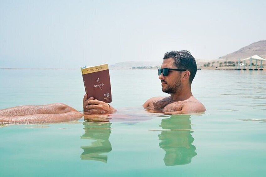 A person in a body of water reading a book. 1