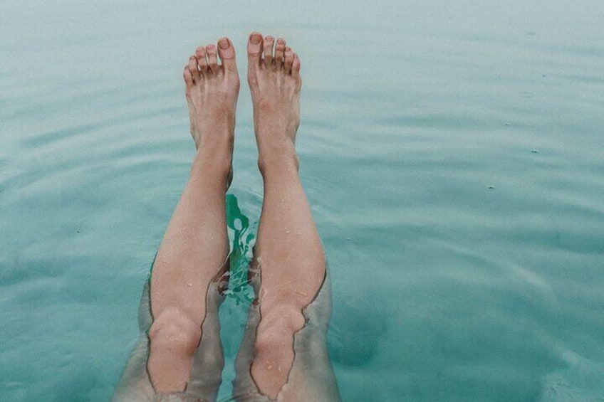 A pair of legs floating in calm turquoise water. 3
