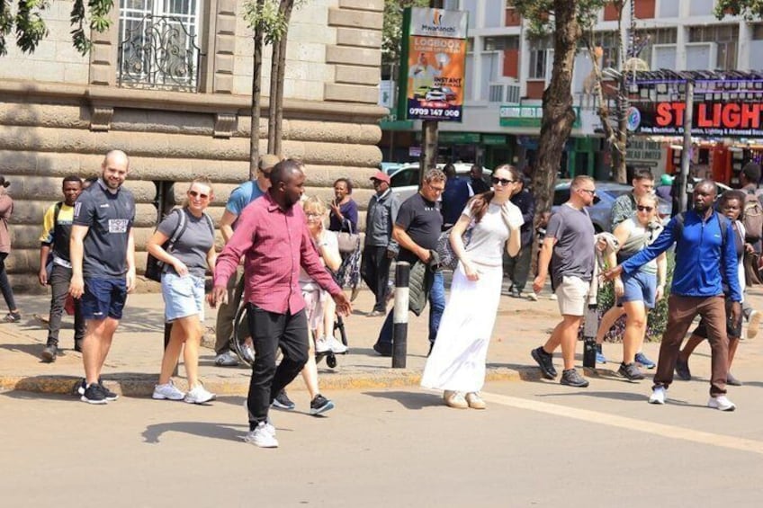 Un groupe de personnes marchant dans une rue bordée d’immeubles, avec une enseigne indiquant « ST LIGHT ». 3