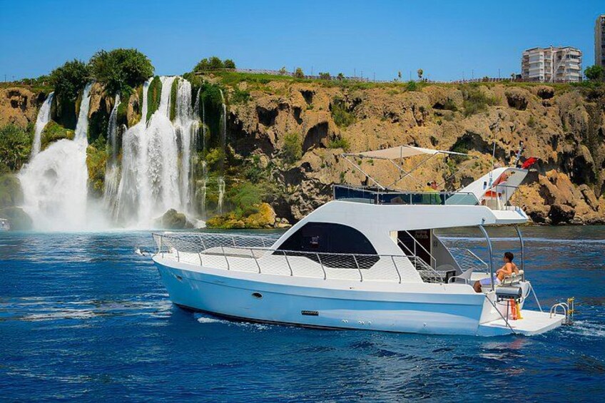 A white boat on calm water with a waterfall in the background. 2
