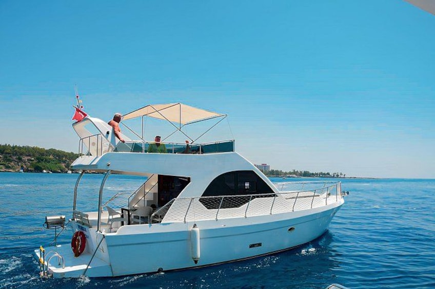 A white motorboat on calm water with a canopy and a person standing on the deck. 4