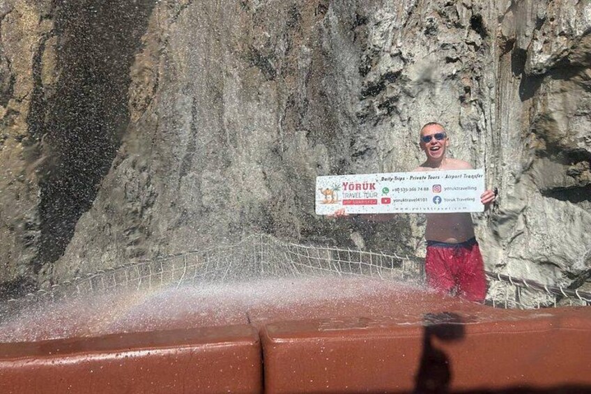 A person holding a large check in front of a rocky cliff. 3