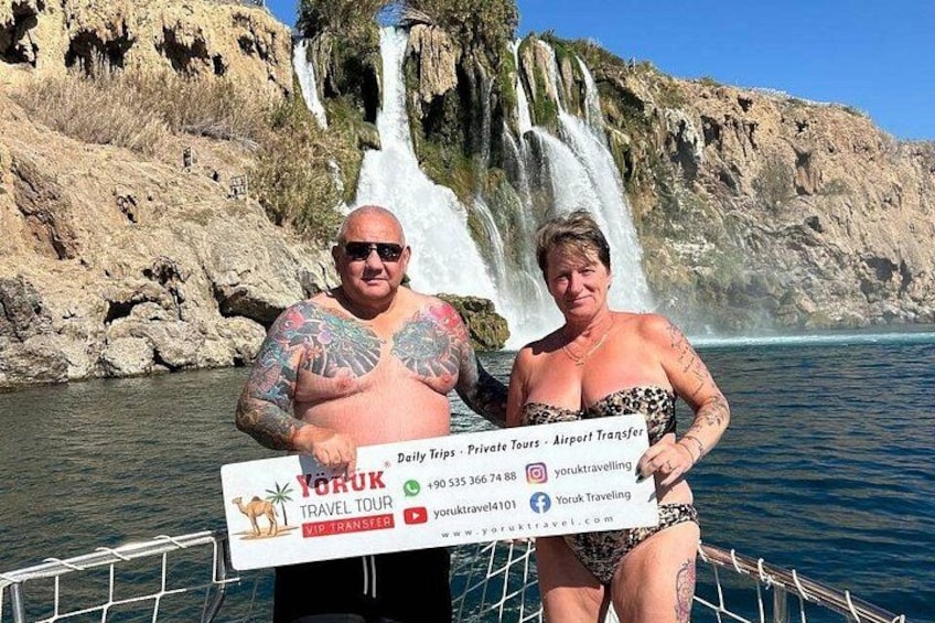 Two people holding a large check in front of a waterfall. 2