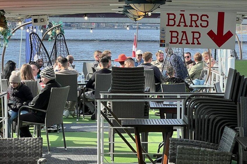 Un espace bar avec des chaises et des tables en osier, donnant sur un plan d’eau. 4