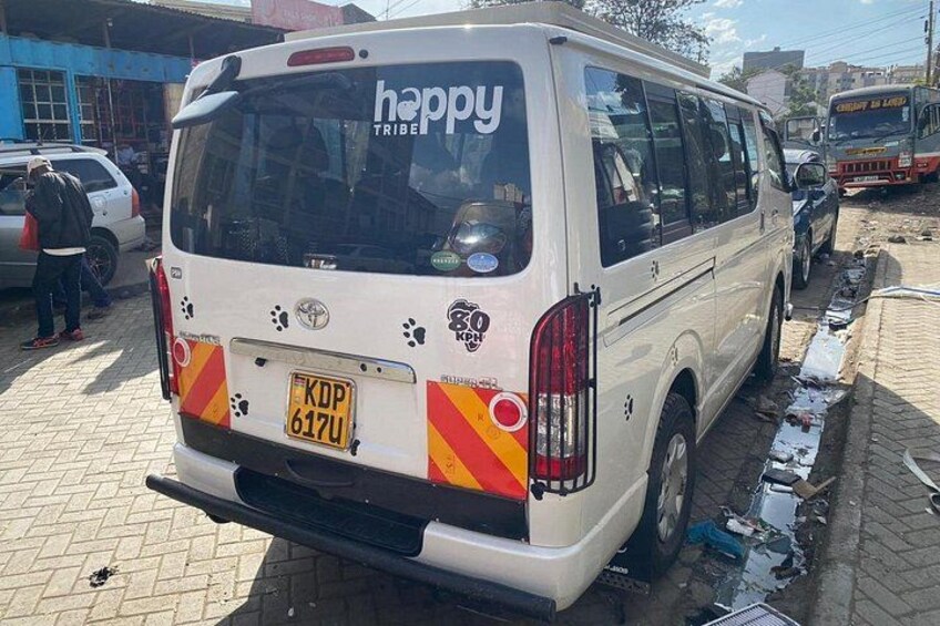 A white van with 'happy tribe' written on the back, parked on a street with visible tire tracks and debris. 3