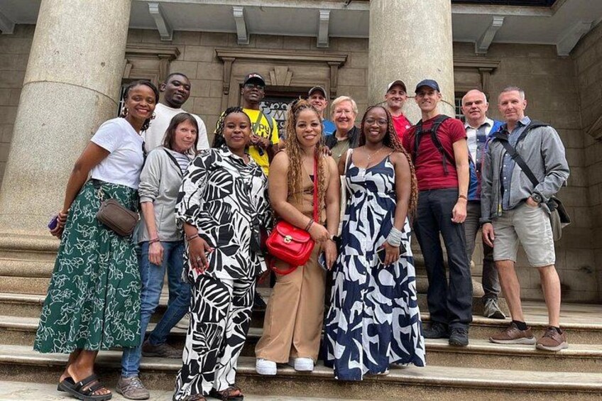 A group of people standing on steps in front of a building with columns. 1