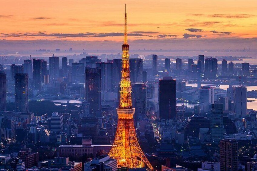 Un paisaje urbano con una torre iluminada destacada, probablemente un punto de referencia famoso, rodeado de numerosos edificios altos y una masa de agua al fondo. 3