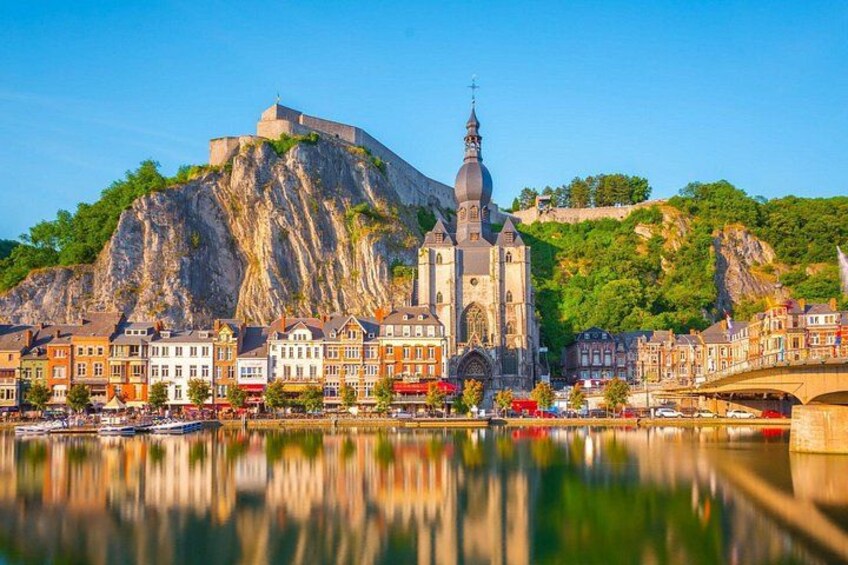 A historic cityscape with a prominent church, a castle on a hill, and a river reflecting the buildings. 1