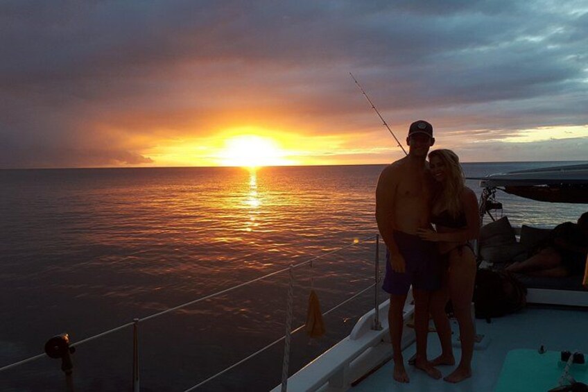 Ein Sonnenuntergang über dem Meer mit einem Boot und Personen an Deck. 4
