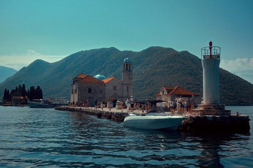A coastal town with a prominent church, a lighthouse, and boats on the water. 4