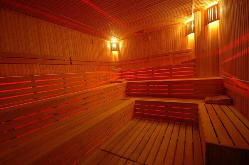 Een houten sauna met banken en rode verlichting. 5