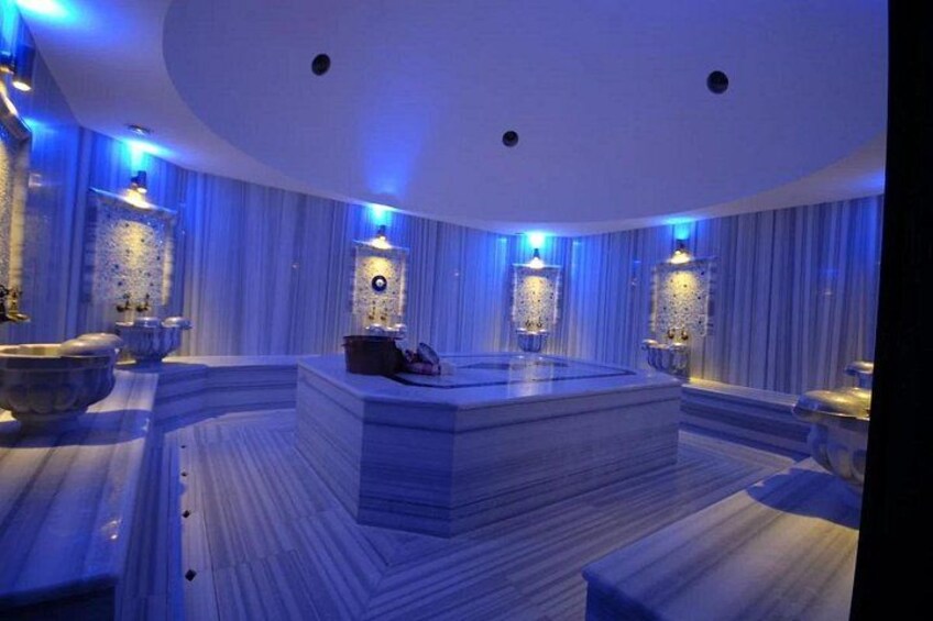 Een luxe badkamer met een centraal gelegen whirlpool, marmeren vloeren en decoratieve verlichting. 3