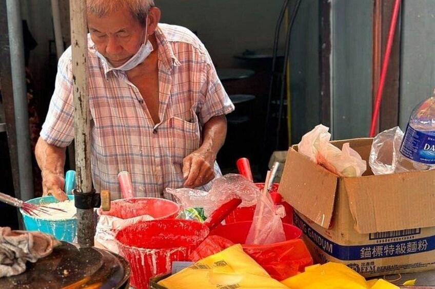 A person preparing food at a stall with various containers and utensils. 2