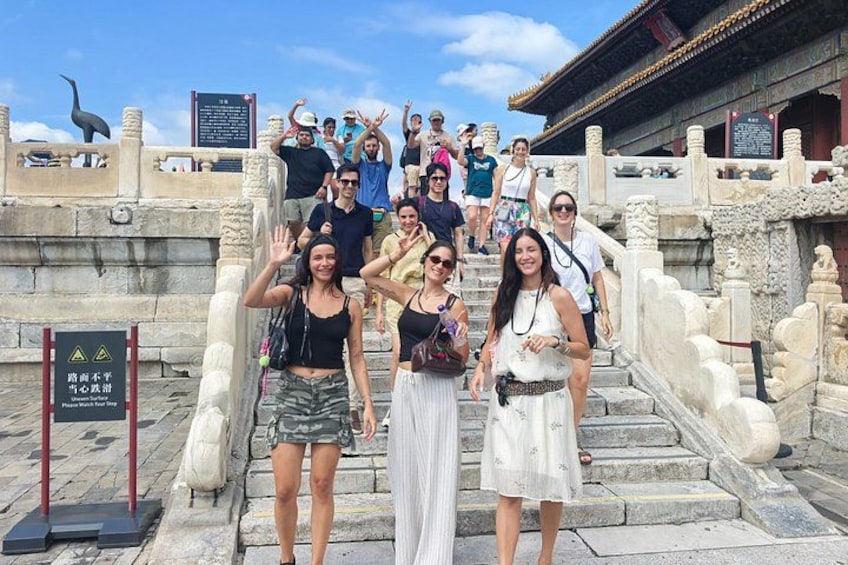 A group of people on stone steps with traditional architecture in the background. 1