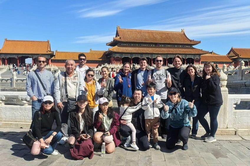 A group of people posing in front of a traditional Chinese architectural structure with a tiled roof and ornate details. 3