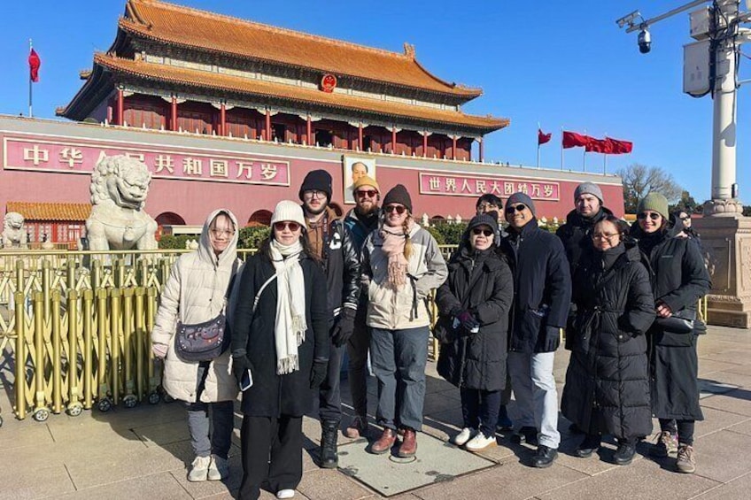 A group of people standing in front of a traditional Chinese building with a lion statue. 3