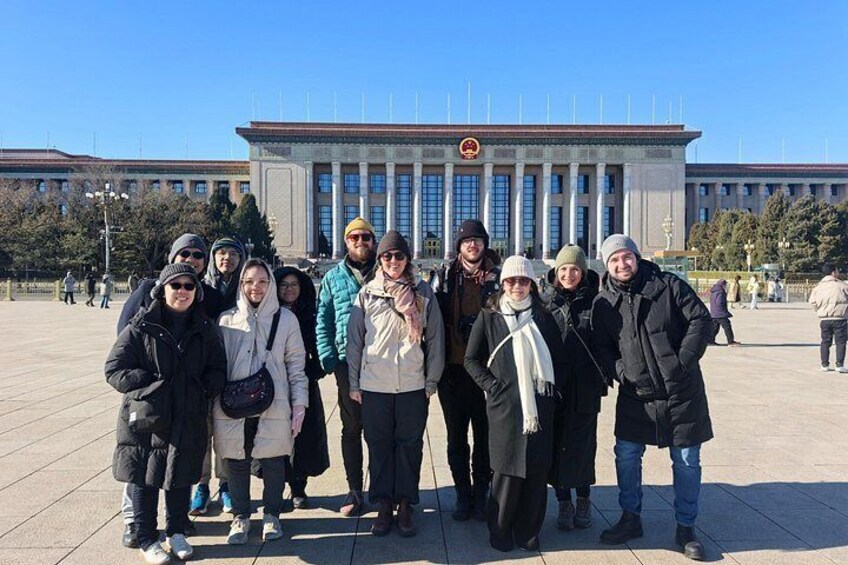 A group of people standing in front of a large building with columns and a flag. 2