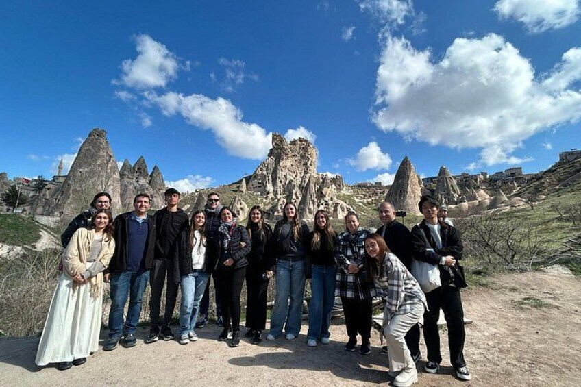 A group of people standing in a rocky landscape with prominent rock formations in the background. 2