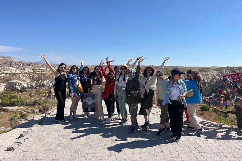 A group of people standing on a paved area with a rocky landscape in the background. 3