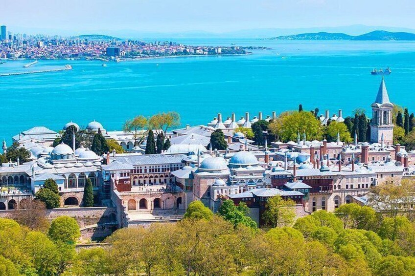 A coastal cityscape with historic architecture, a prominent tower, and a clear blue sea. 3